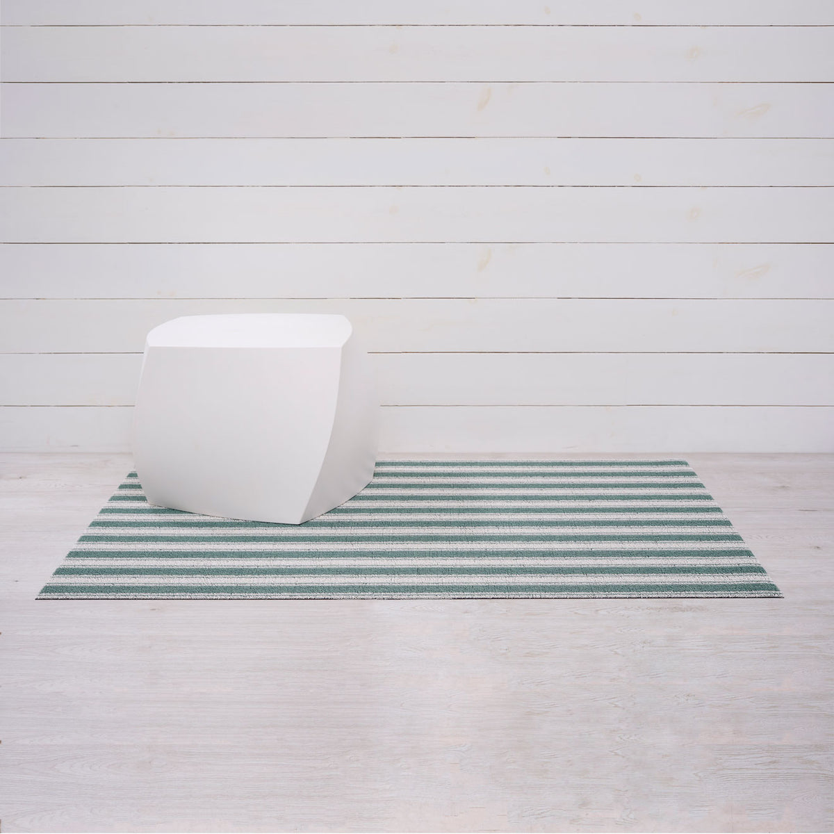 Chilewich striped woven mat with textured terrastrand yarn surface, featuring modern linear design and durable finish.