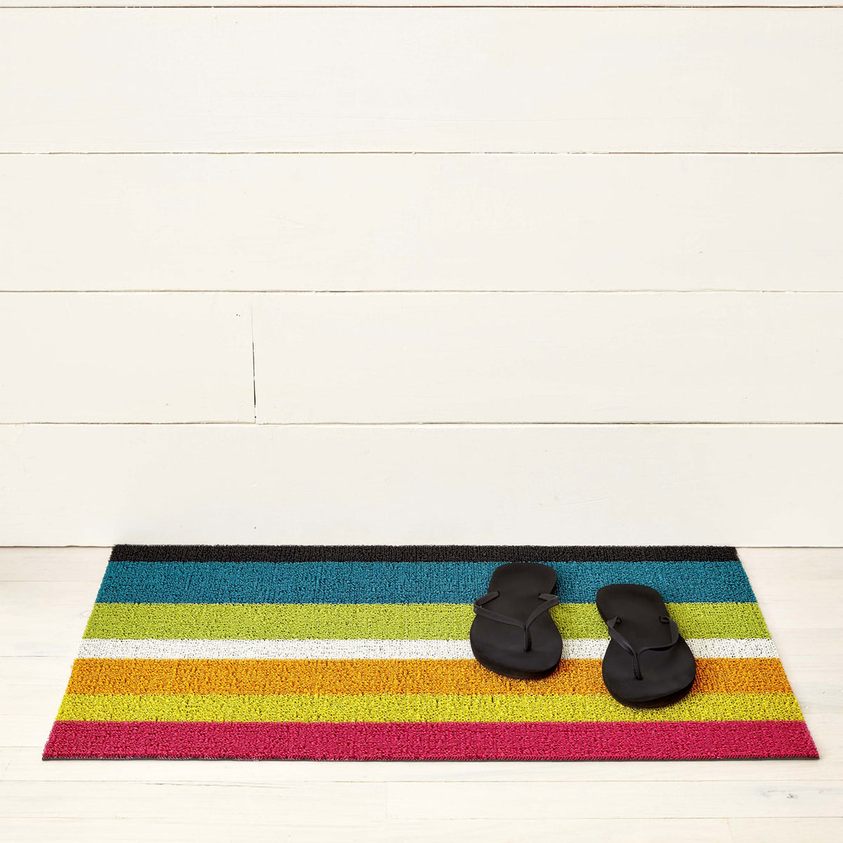 Chilewich striped woven mat with textured terrastrand yarn surface, featuring modern linear design and durable finish.