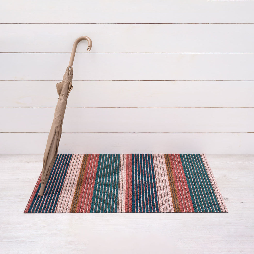 Chilewich striped woven mat with textured terrastrand yarn surface, featuring modern linear design and durable finish.